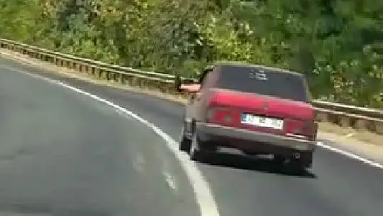 Ayaklarını camdan sarkıtarak trafiği tehlikeye attı