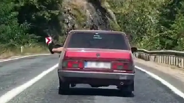 Ayaklarını camdan sarkıtarak trafiği tehlikeye attı